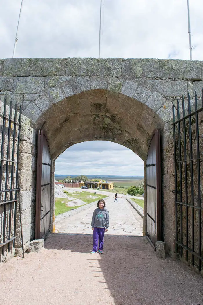 menina em frente a portão de pedra