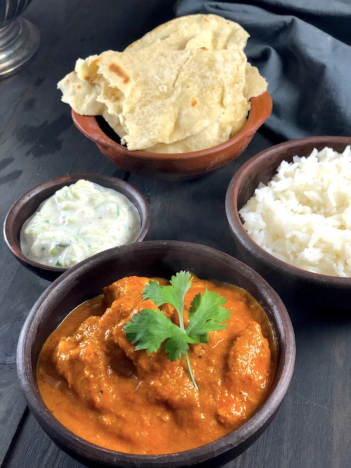 Frango Indiano - Butter chicken - servido em um bowl de barro e acompanhado de arroz, raita e Naan.