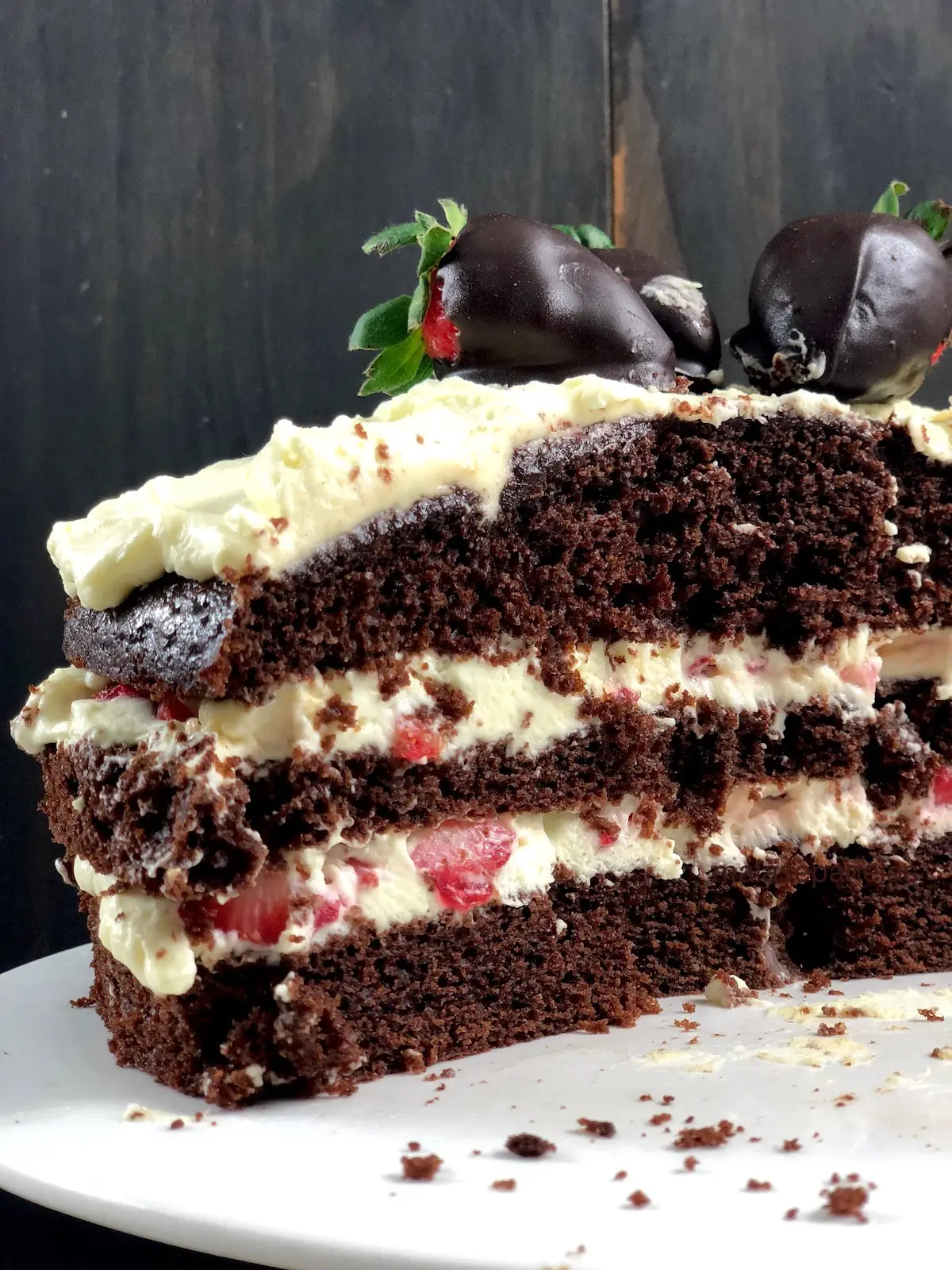Imagem mostrando detalhe da parte interna de bolo de chocolate recheado com pedaços de morangos e chantilly